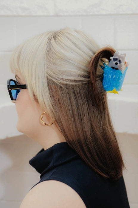 Hair claw worn in a half up hair-do against a light background.