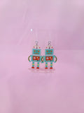 Earrings shown with the plastic hook option against a light pink background