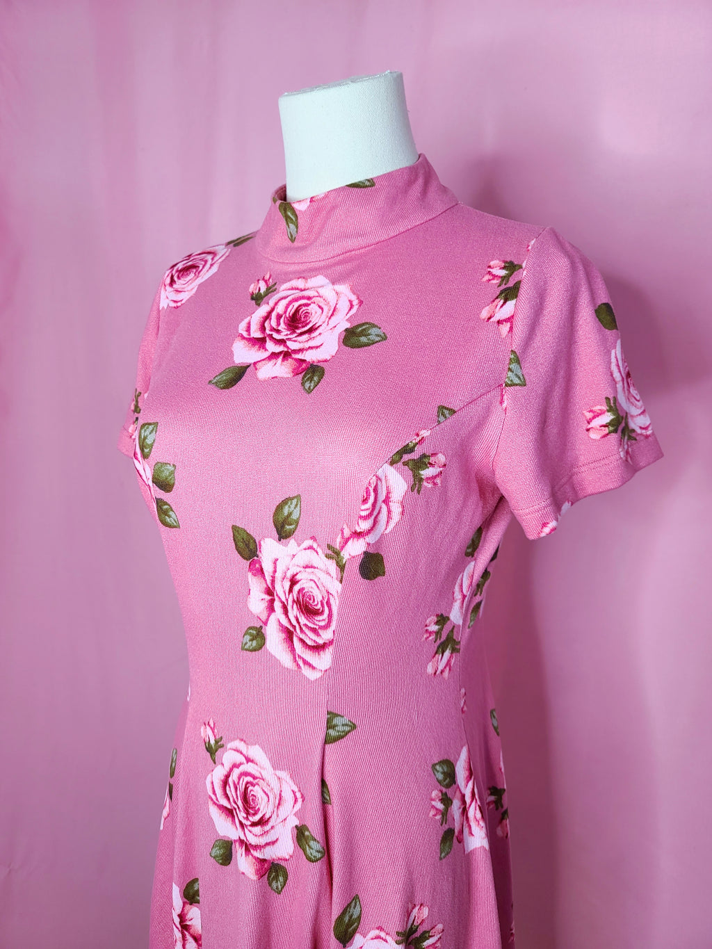 Up close of the front top half of the dress. Dress is on a white mannequin against a light pink background.