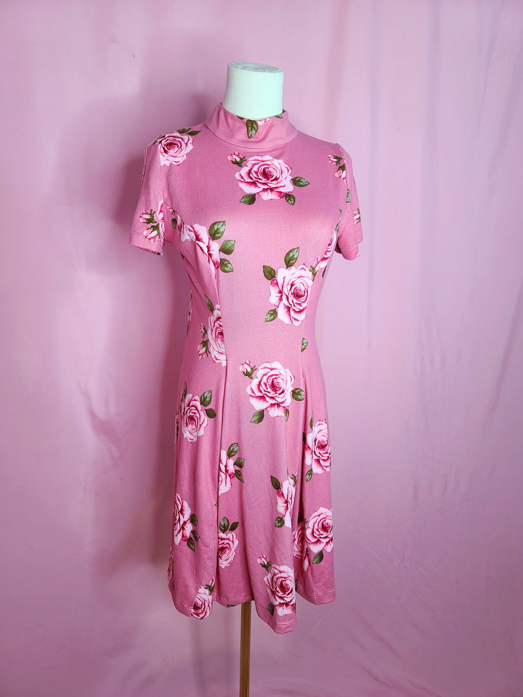 Dress on a white mannequin against a light pink background.