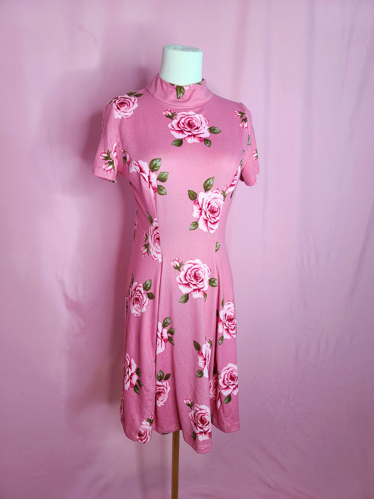 Dress on a white mannequin against a light pink background.