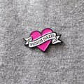 Pink heart with a white banner pin that states "Punch Nazis" against a grey background.