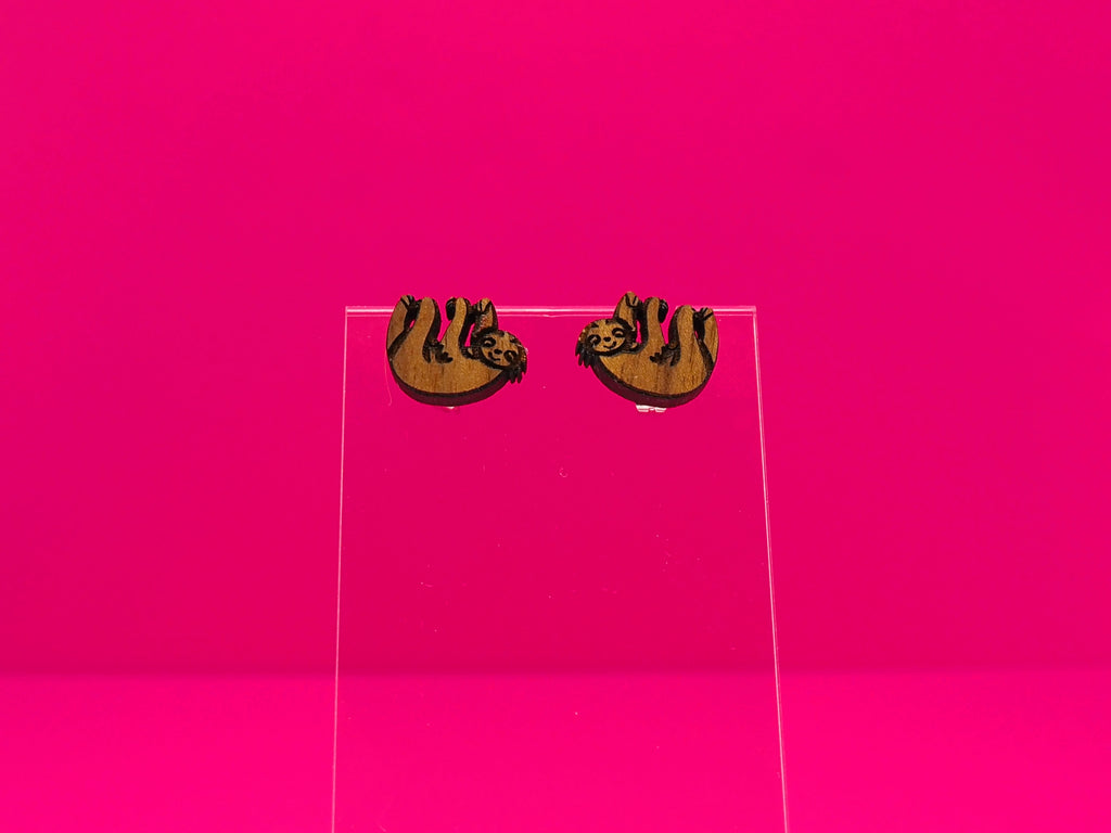 Pair of brown wood sloths on a clear display against a hot pink background.