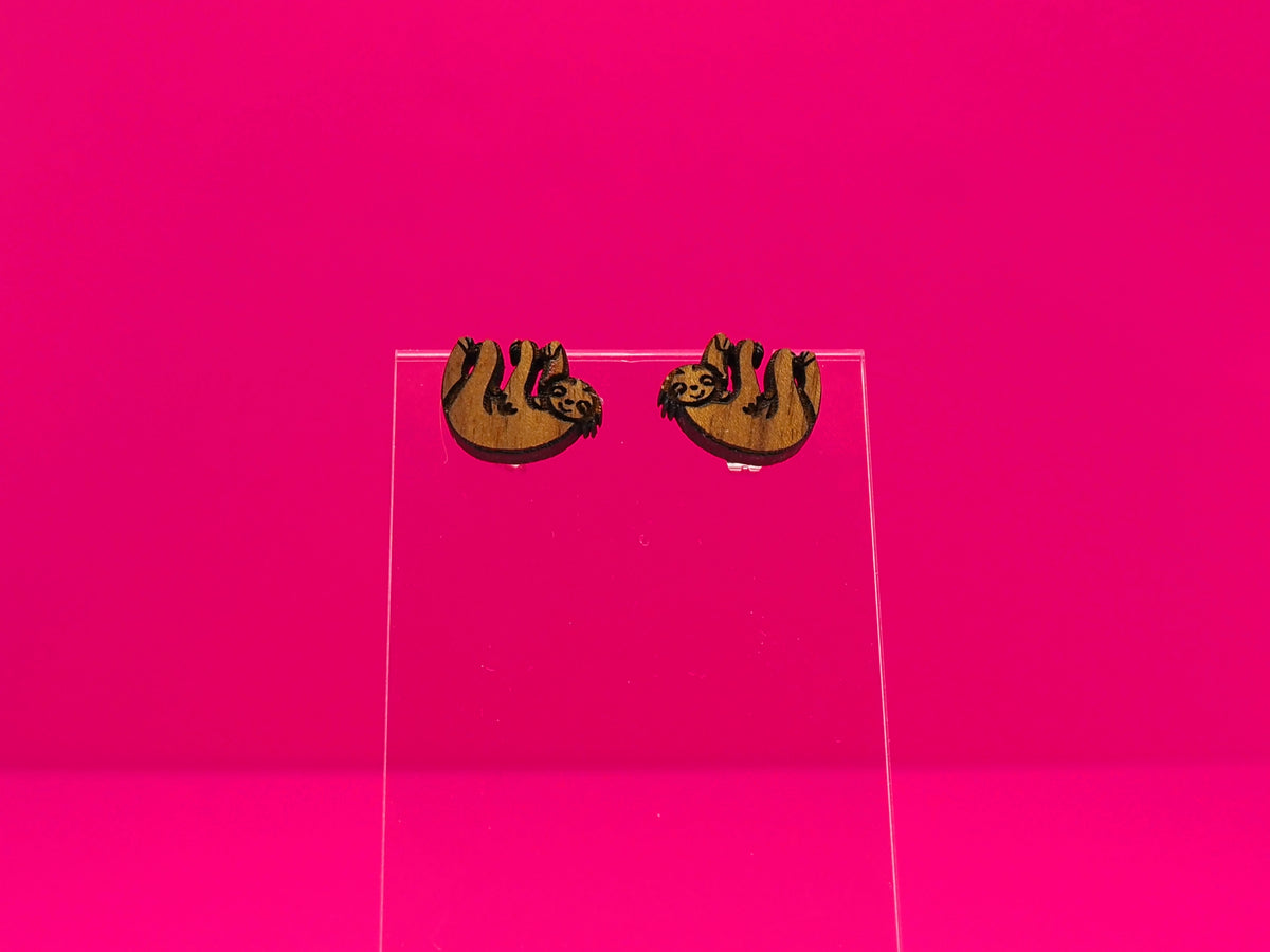Pair of brown wood sloths on a clear display against a hot pink background.