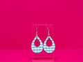 Light blue gingham tear drop shaped earrings on a clear display against a hot pink background.