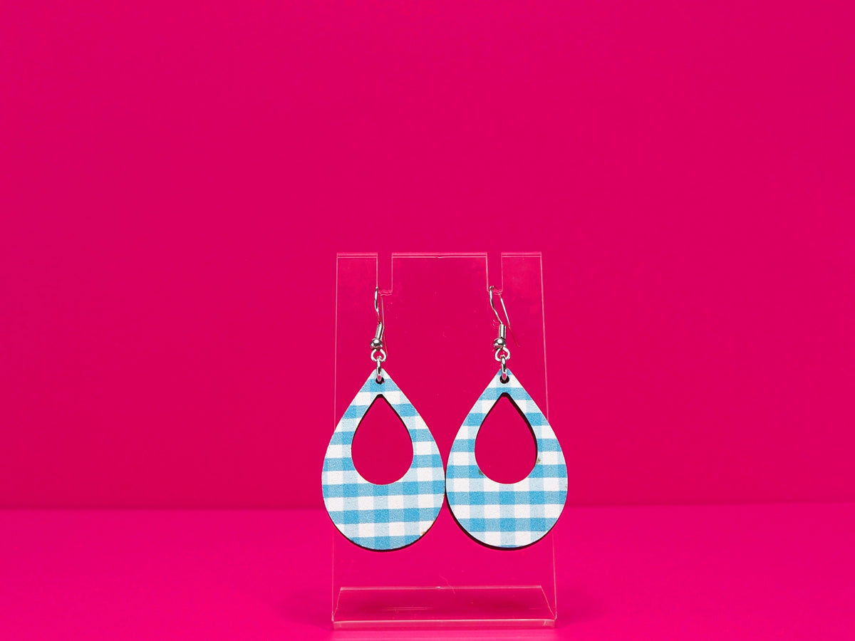 Light blue gingham tear drop shaped earrings on a clear display against a hot pink background.