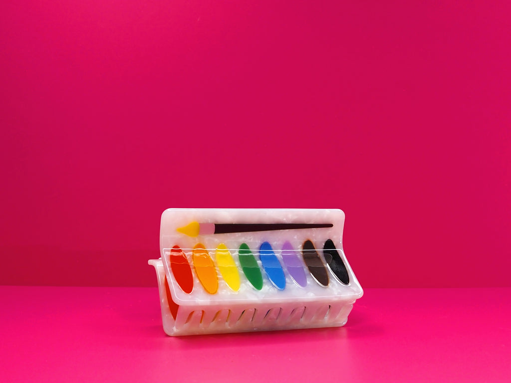 Water color palette hair claw against a pink background.