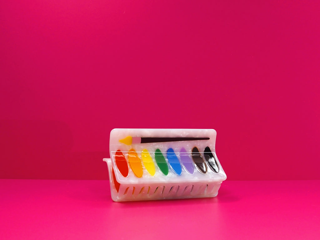 Water color palette haiw claw against a pink background.