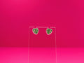 Monstera leaf earrings on a clear display against a pink background.