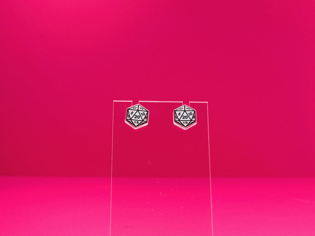D20 dice earrings on a clear display against a pink background.