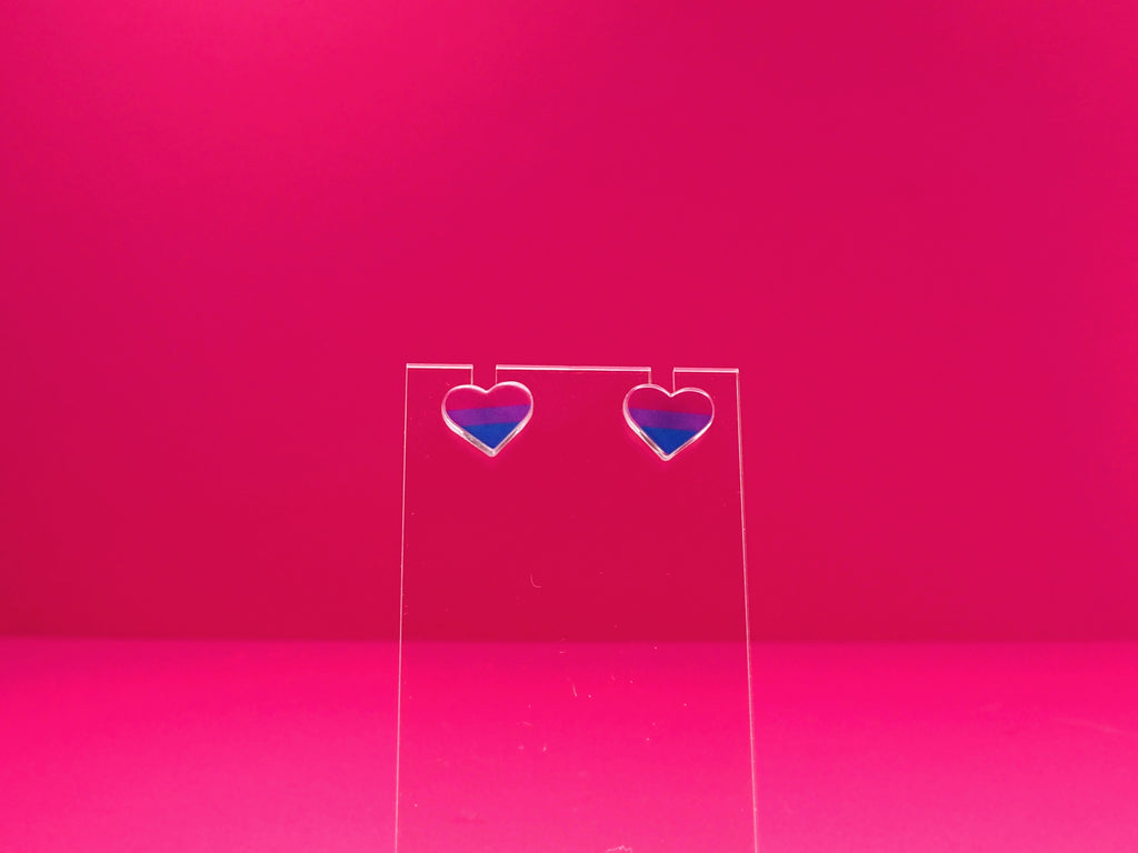 Bisexual pride heart earrings on a clear display against a pink background.