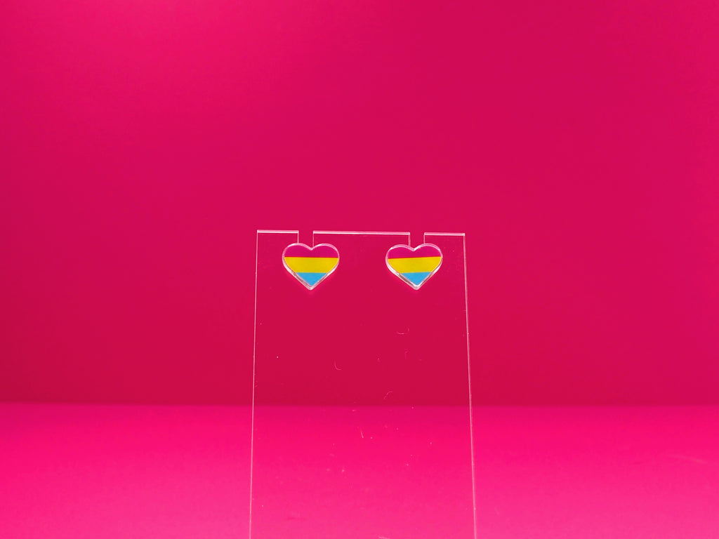 Pansexual pride heart earrings on a clear display against a pink background.
