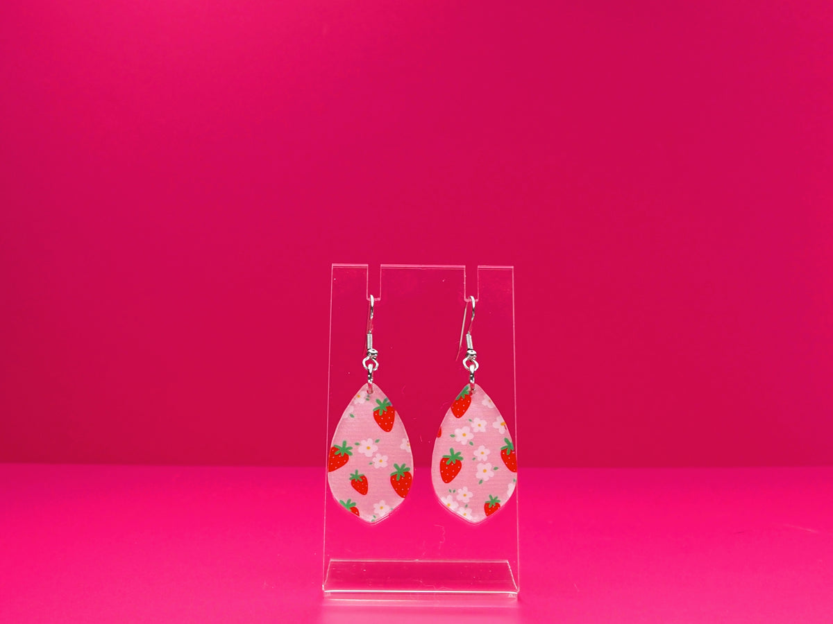 Strawberry Delight earrings on a clear display against a pink background.