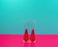 Pink art deco earrings against a blue and pink background.