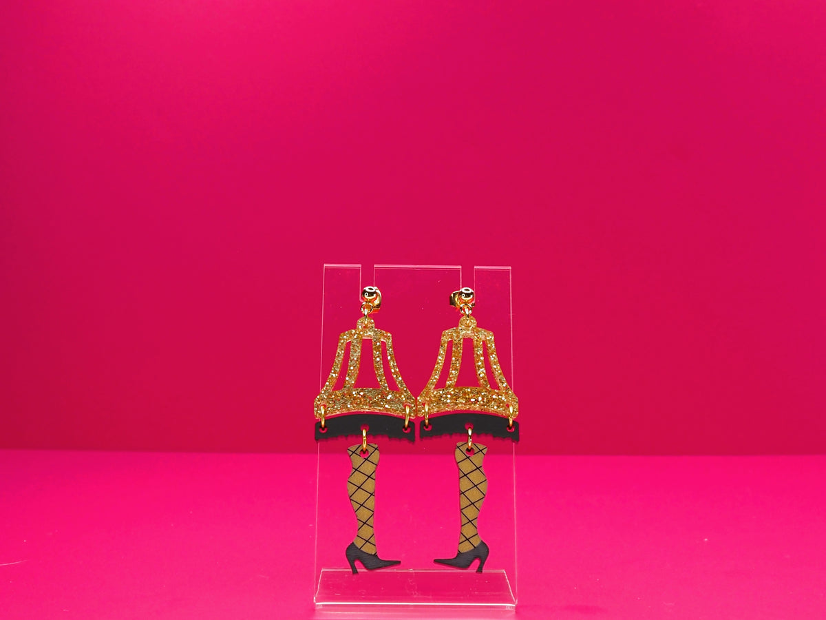 Leg lamp earring on a clear display against a pink background.