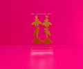 Dinosaur nugget earrings on a clear stand against a pink background.