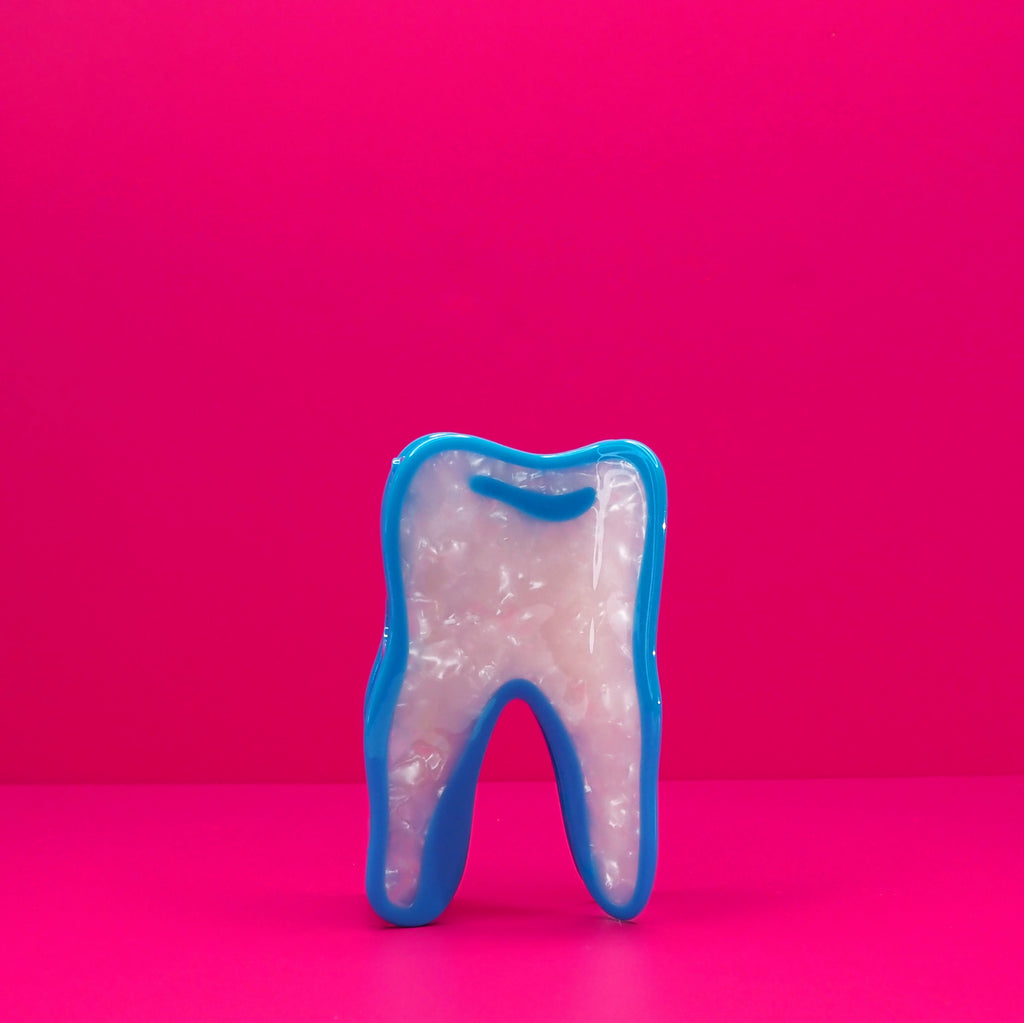 Wisdom tooth hair claw against a pink background.