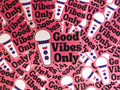 Die cut sticker that says 'Good vibes only' in black text with a pink background surrounded by the same sticker as a background.