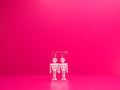 White acrylic skeleton earrings on a clear display against a pink background.