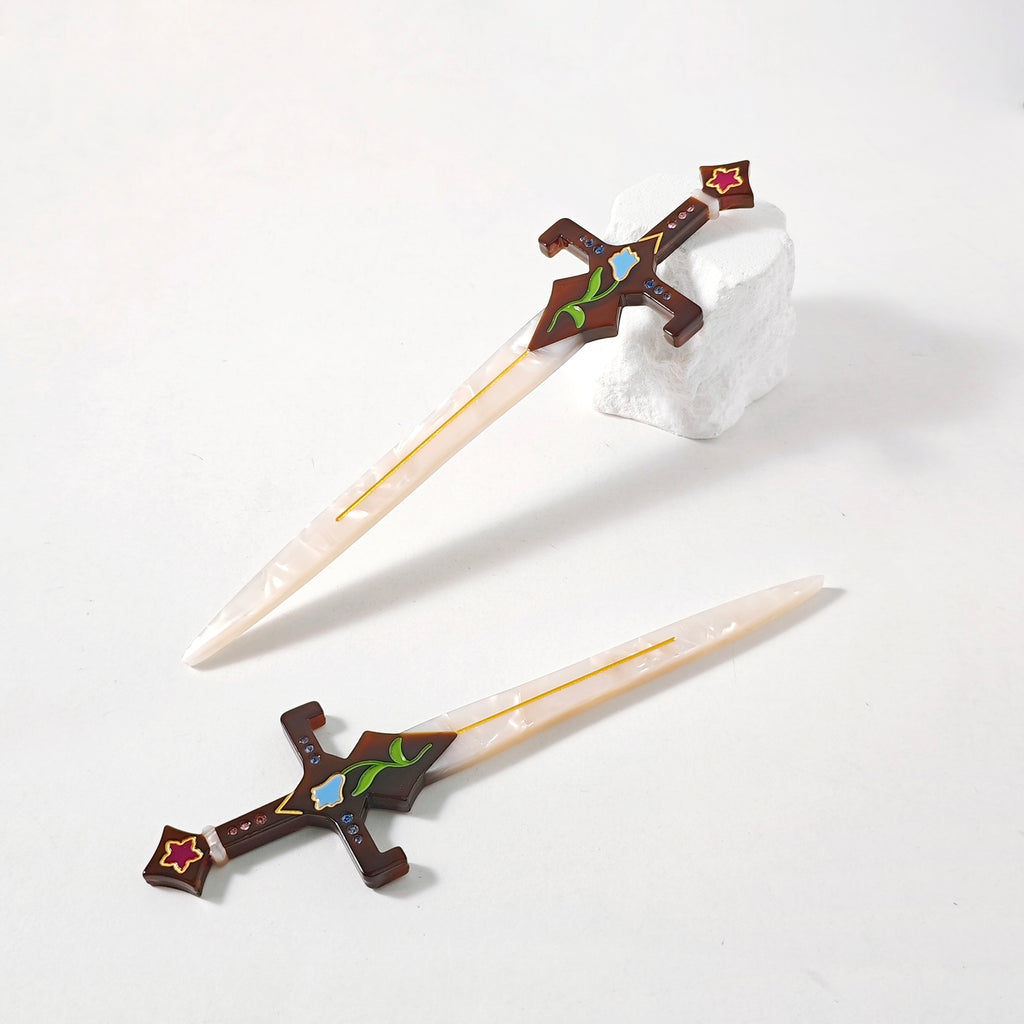 Two hair swords with one resting on a white stone against a white background.