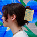 Brunette hair model wearing the library card hair claw against a colorful background.