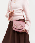 Model wearing purse at side against a white background.