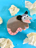 Hair claw shown against a light blue background surrounded by crumpled paper