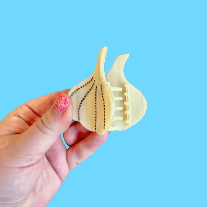 Hand holding the hair claw open against a blue background