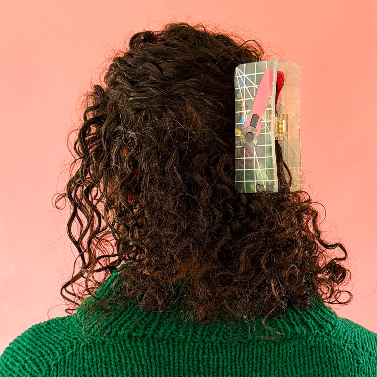 Brunette model wearing hair claw against a pink background.