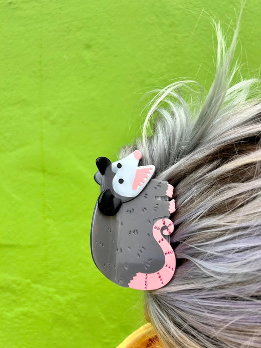 Hair claw in use by a model with grey hair against a bright green background.