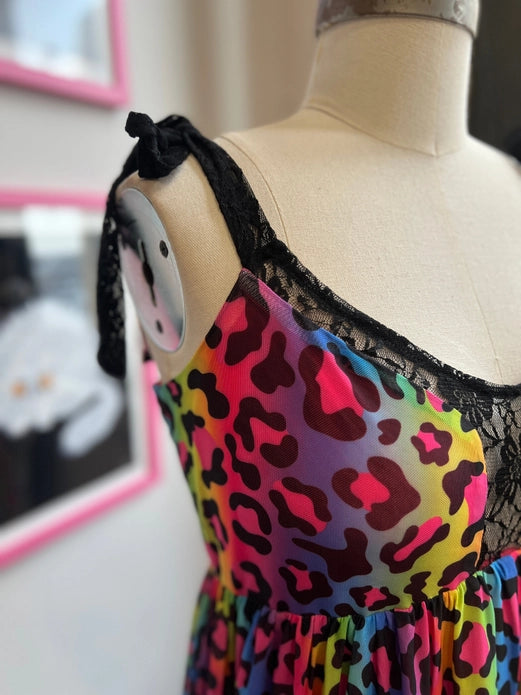 Close up of the front shoulder of the dress on a white mannequin. Showing the details of the rainbow leopard print, and the black lace details.
