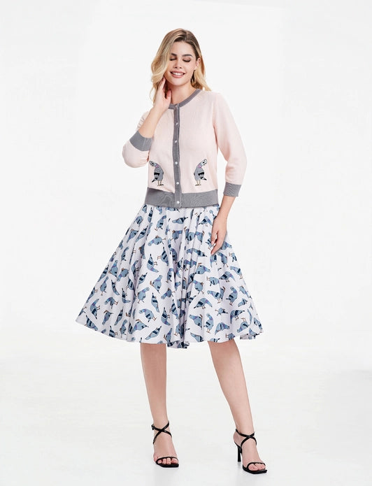 Woman wearing pigeon cardigan and dress against a white background.