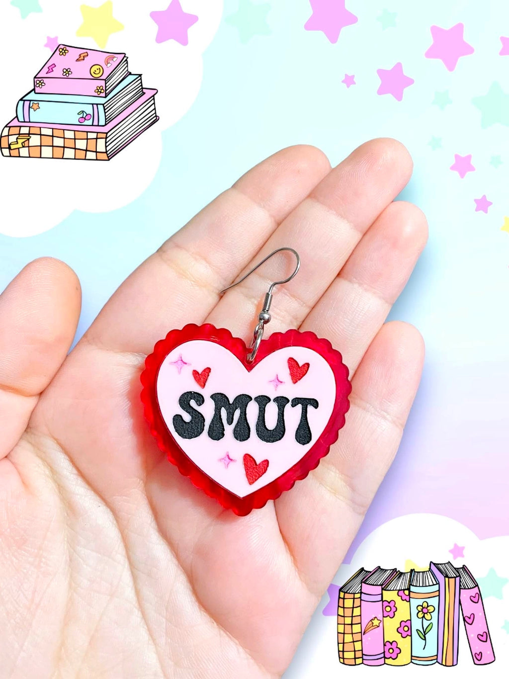 Pink heart earring with red lace edges and the word "Smut" in a funky black font on a white model's hand against a bright background.