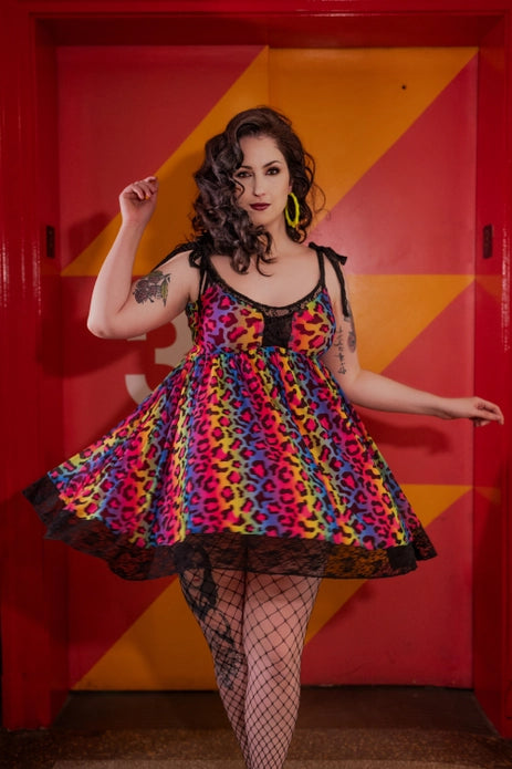 A fair skin model with dark curls showing the front of the dress against a bright red and yellow background.