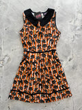 Front of orange, black, and white dress against a light concrete background.