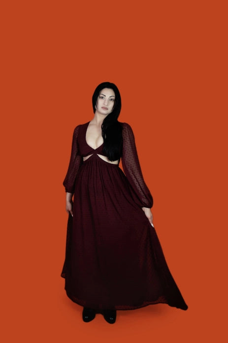 Woman wearing a burgundy dress against an orange background.