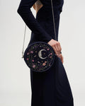 Model in a dark dress wearing the purse at their side against a white background.