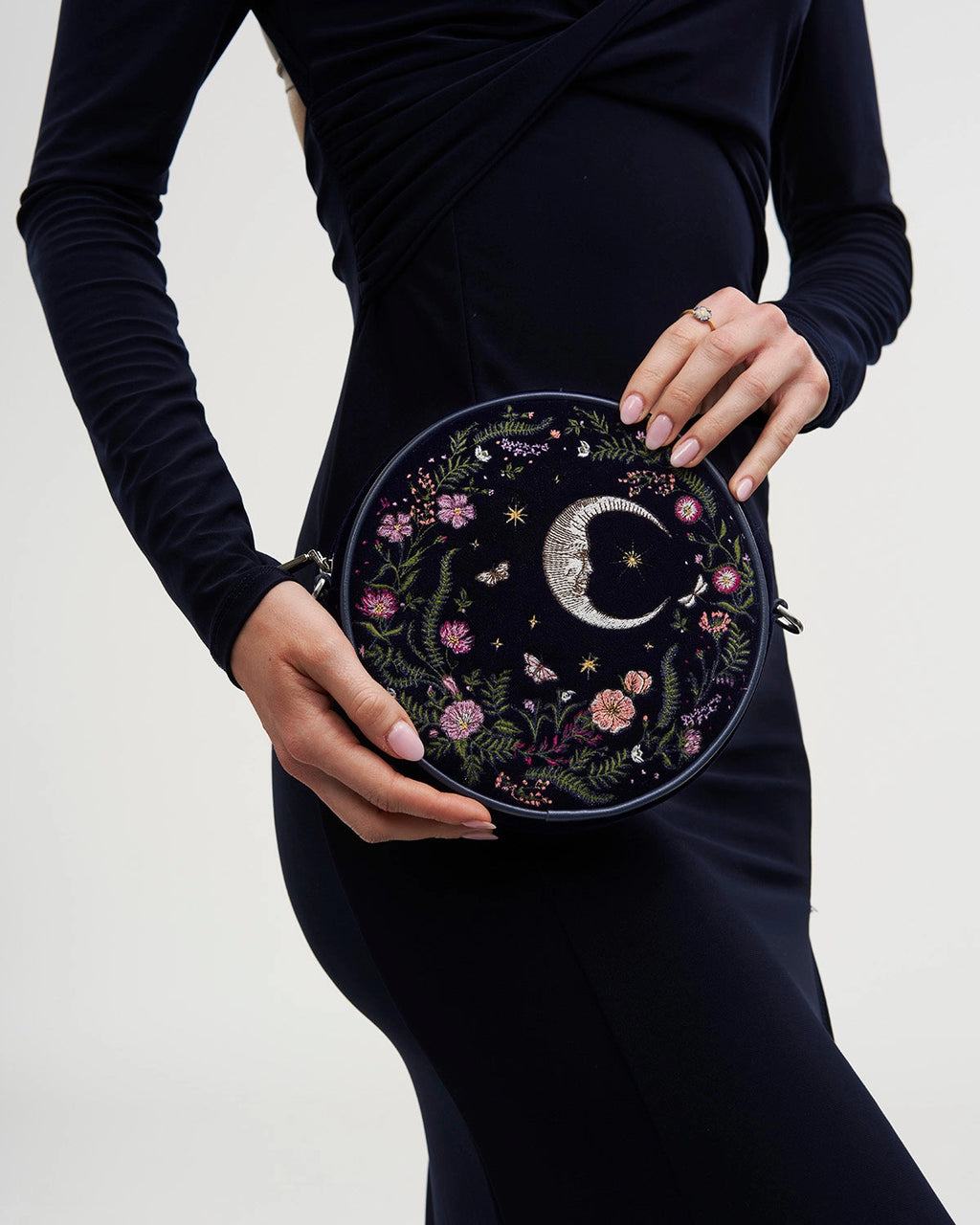 Model holding purse against their side against a white background.