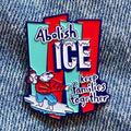 Red and blue enamel pin featuring the text 'Abolish ICE keep families together' with a cartoon polar bear surfing on ice.