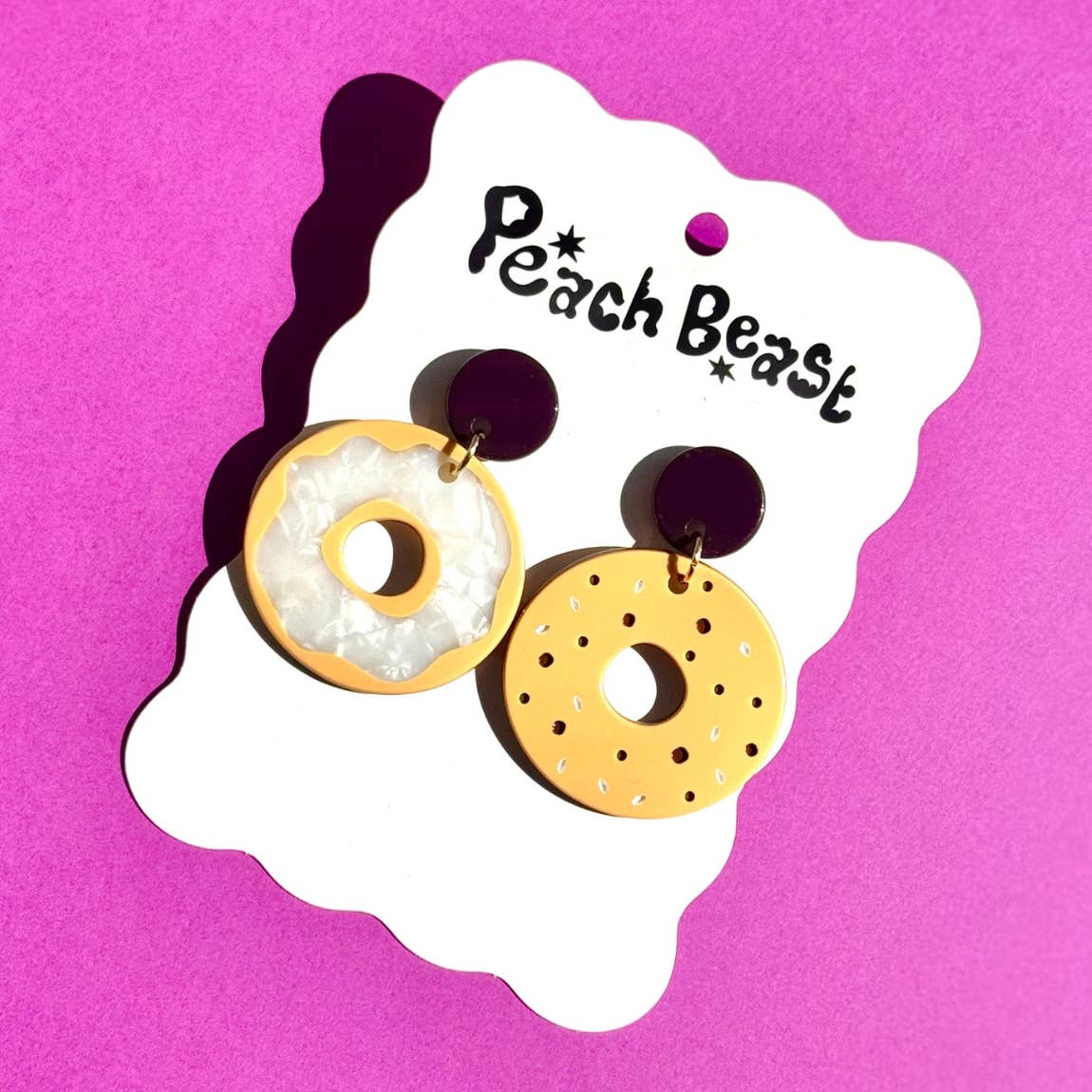 Bagel earrings on a white backing card against a bright purple background.