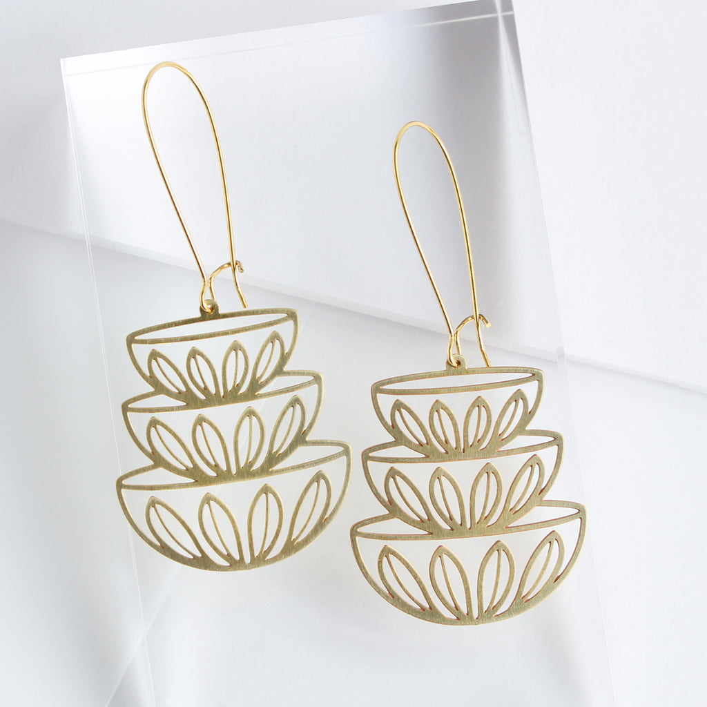 This photo showcases the Stacked Bowl Earrings up close to see the details easier. Bowls are a stack of three in gold with flower petals along the bottom of each bowl