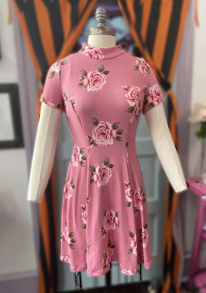 Dress on a white mannequin. Dress is a dusty rose pink with light pink roses